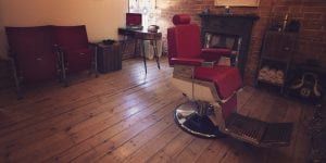 Barbers shop waiting area with a record player int he background and a red barbers chair