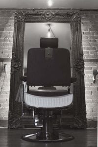 Black and White portrate photo of a Barbers Chair with a mirror in the background